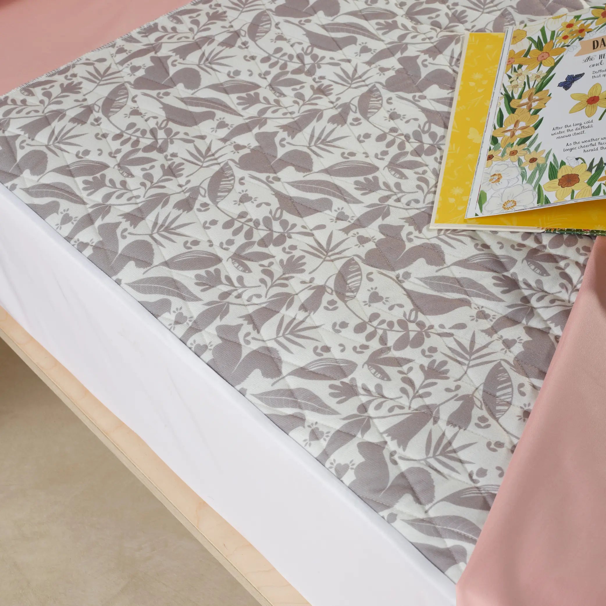 Close-up of a children's waterproof absorbent kylie bed pad featuring a soft, nature-inspired printed design. This reusable, washable incontinence pad offers leak-proof mattress protection, ideal for toilet training and night-time accidents.