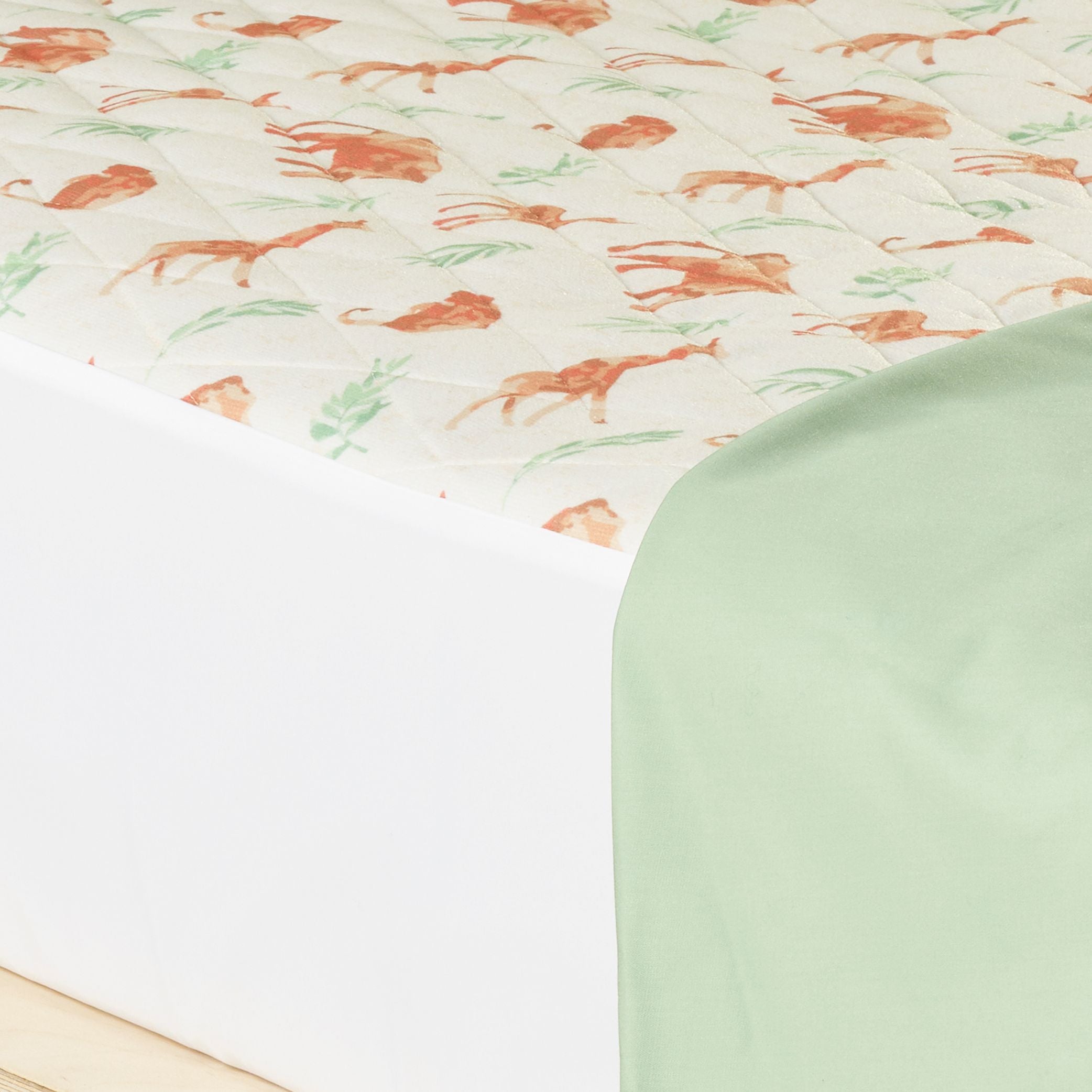 Close-up of a children's waterproof absorbent Kylie bed pad featuring a safari animal print with earthy tones. This reusable leak-proof mattress protector is designed for toilet training, bedwetting, and incontinence protection.