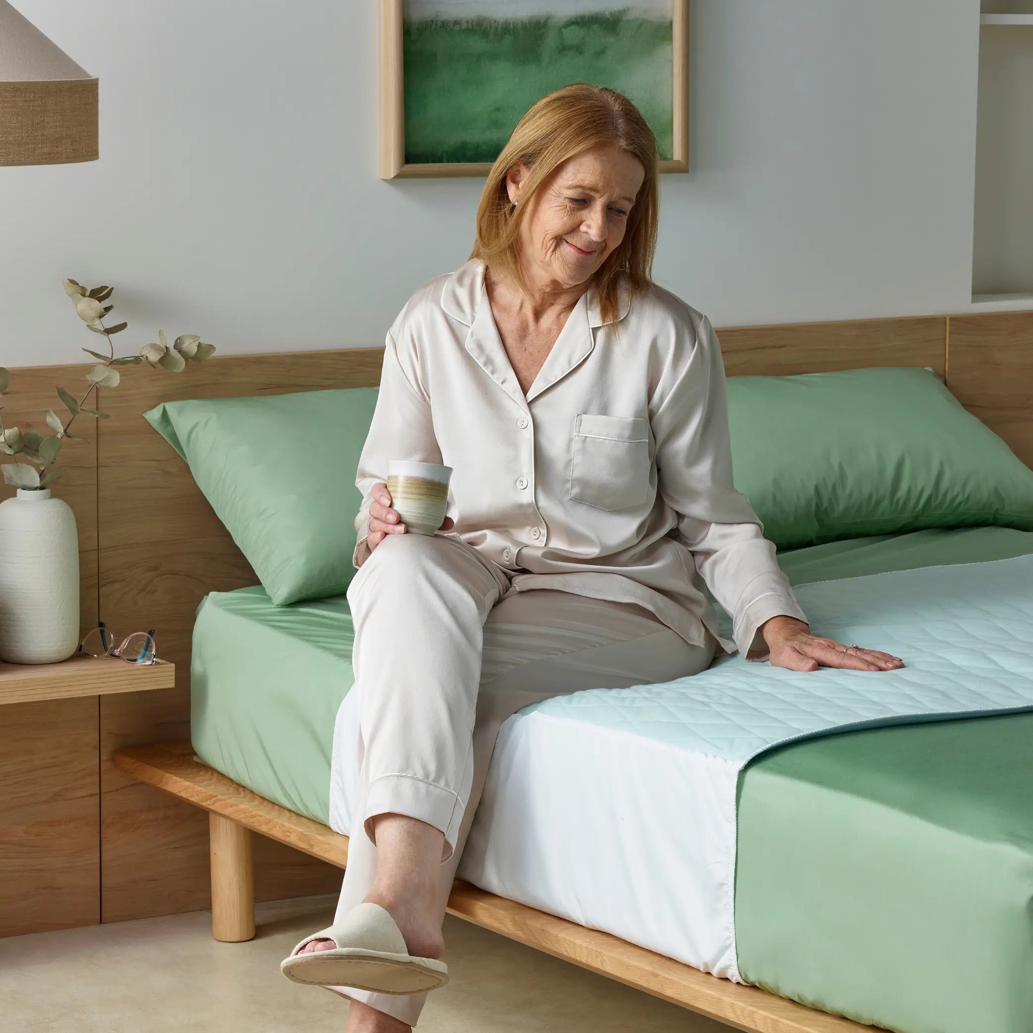 Senior woman enjoying a comfortable rest on a lightweight blue waterproof bed pad. Known as Kylie Bed Pad. This absorbent incontinence bed pad provides soft, breathable, and leak-proof protection for better sleep quality.