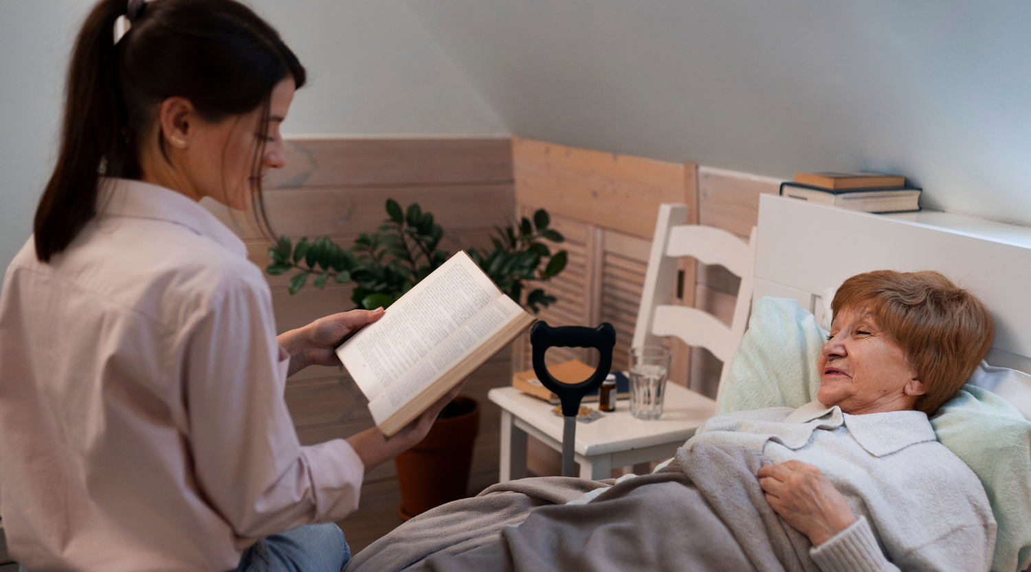 woman reading to an elderly woman in bed