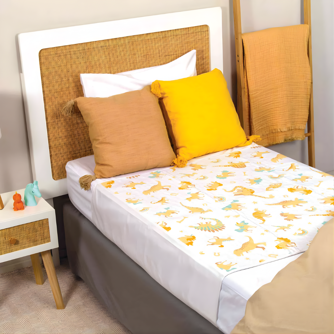 Conni Kids Bed Pad with tuck-ins, unicorn and dinosaur prints, reusable waterproof protection for children’s nighttime comfort and mattress safety.