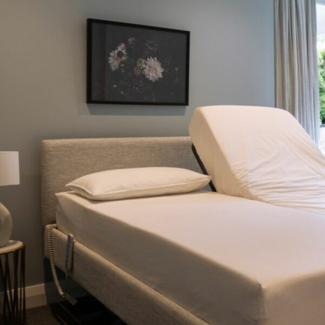 Icare IC333 Homecare Bed shown with adjustable backrest and leg rest, featuring upholstered finish and ultra-low height for safe mobility.