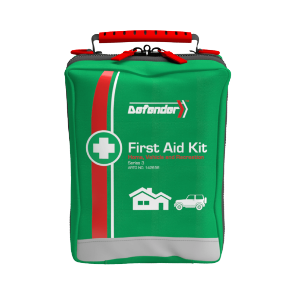 A close-up of the green, zippered softpack carrying case for the Defender Series 3 First Aid Kit. The bag features a red handle, a white first aid cross, a white and red vertical stripe, and is labeled for Home, Vehicle, and Recreation with corresponding icons.