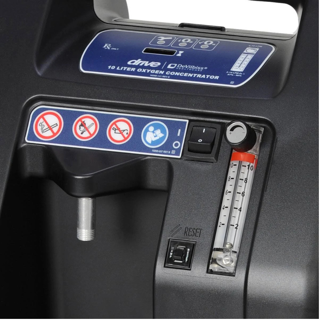 Close-up of Drive DeVilbiss Oxygen Concentrator showing flow meter, power switch, and safety warning labels for oxygen therapy.
