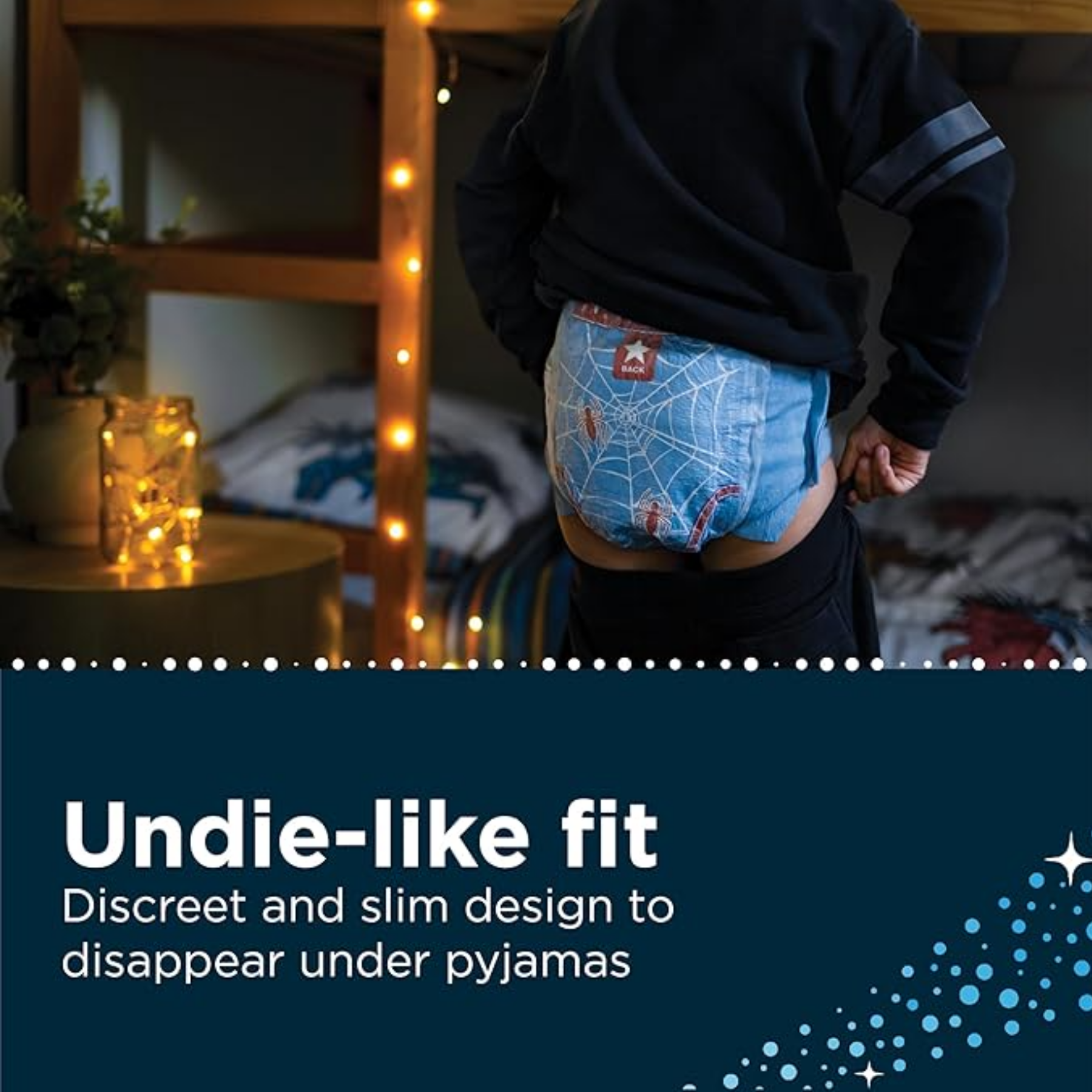 A child wearing a blue Spider-Man patterned DryNites night time pant, demonstrating the slim, discreet "undie-like fit" that disappears under pajamas.