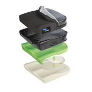 An exploded view of an Invacare Matrx cushion showing the mesh outer cover partially unzipped, the moisture-resistant inner cover, a green foam layer, and a white base layer with a removable circular foam insert.