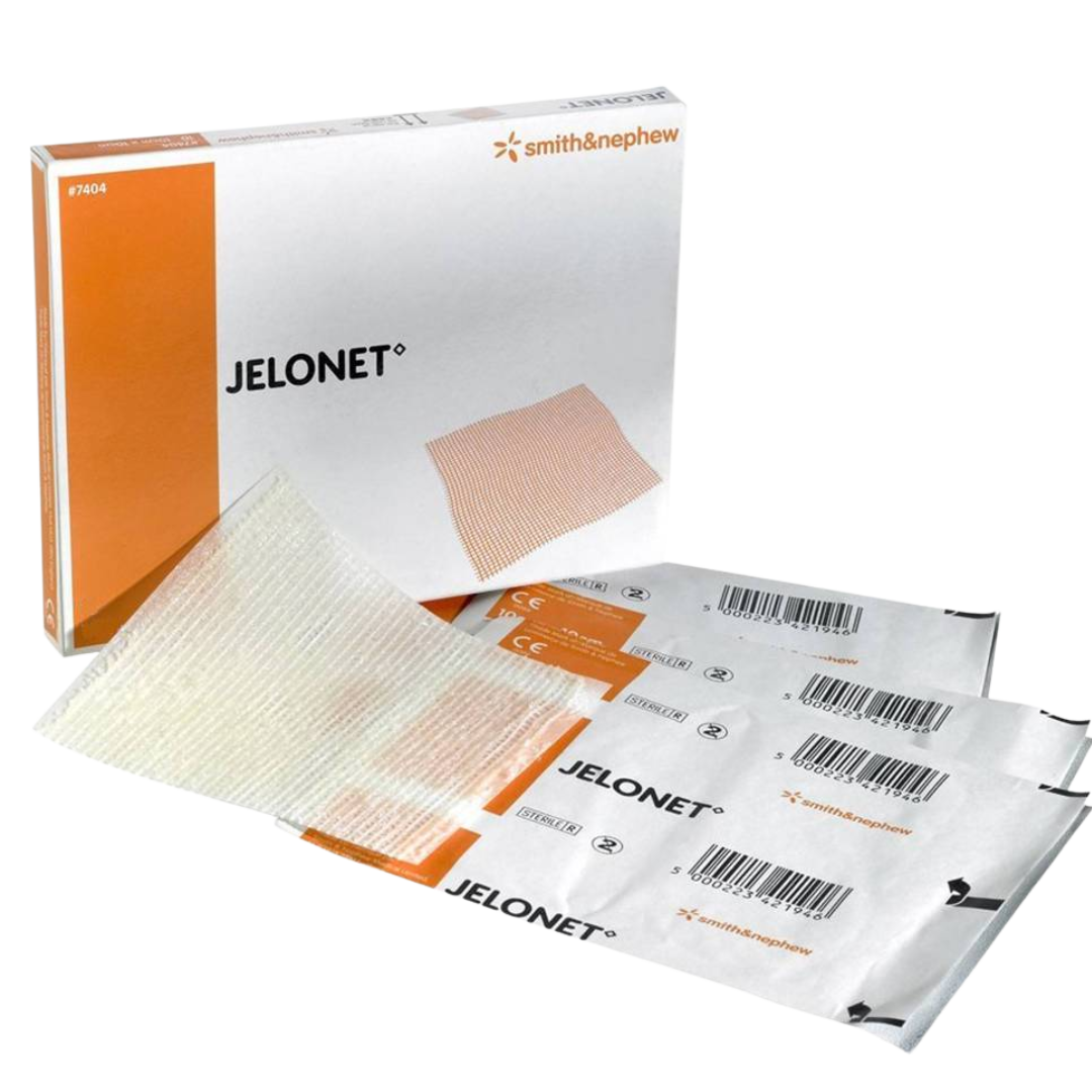 A white and orange box of Jelonet Paraffin Gauze Dressings, with two individually packaged, sterile dressings stacked in front of it. The gauze material is visible on top.