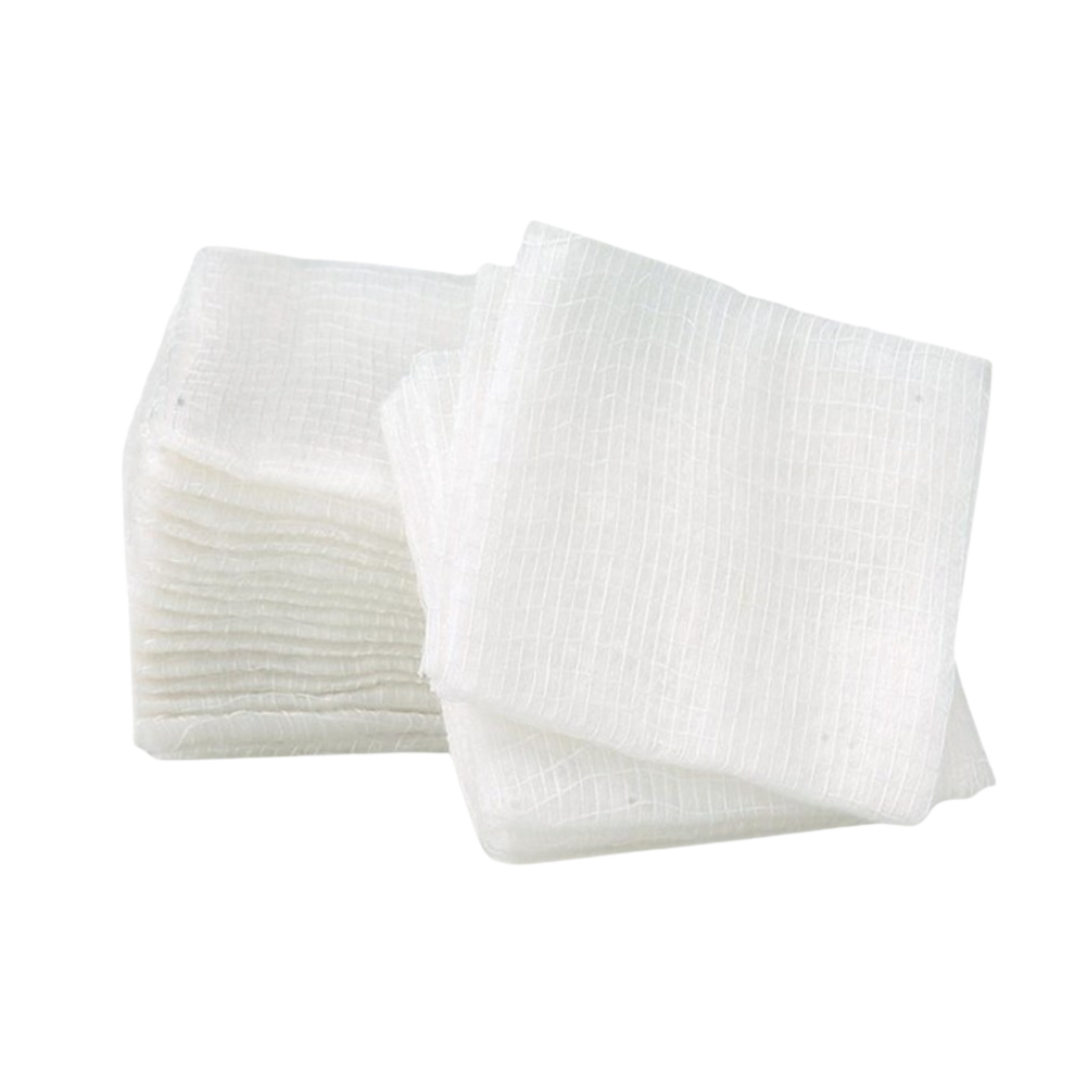 Close-up stack of several folded white non-woven gauze swabs, showing the texture and 8-ply thickness, used for wound management.